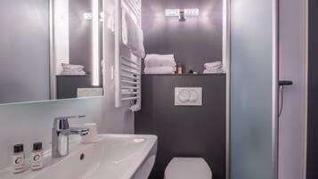A modern bathroom with a sink, mirror, towel rack, and toilet.