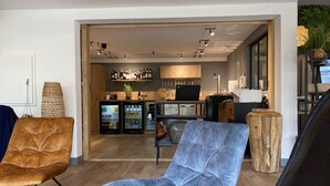 A modern living room with two chairs, a bar area with a laptop, and a refrigerator. - Sure Hotel by Best Western Angers Sud (Les Ponts-de-Ce)