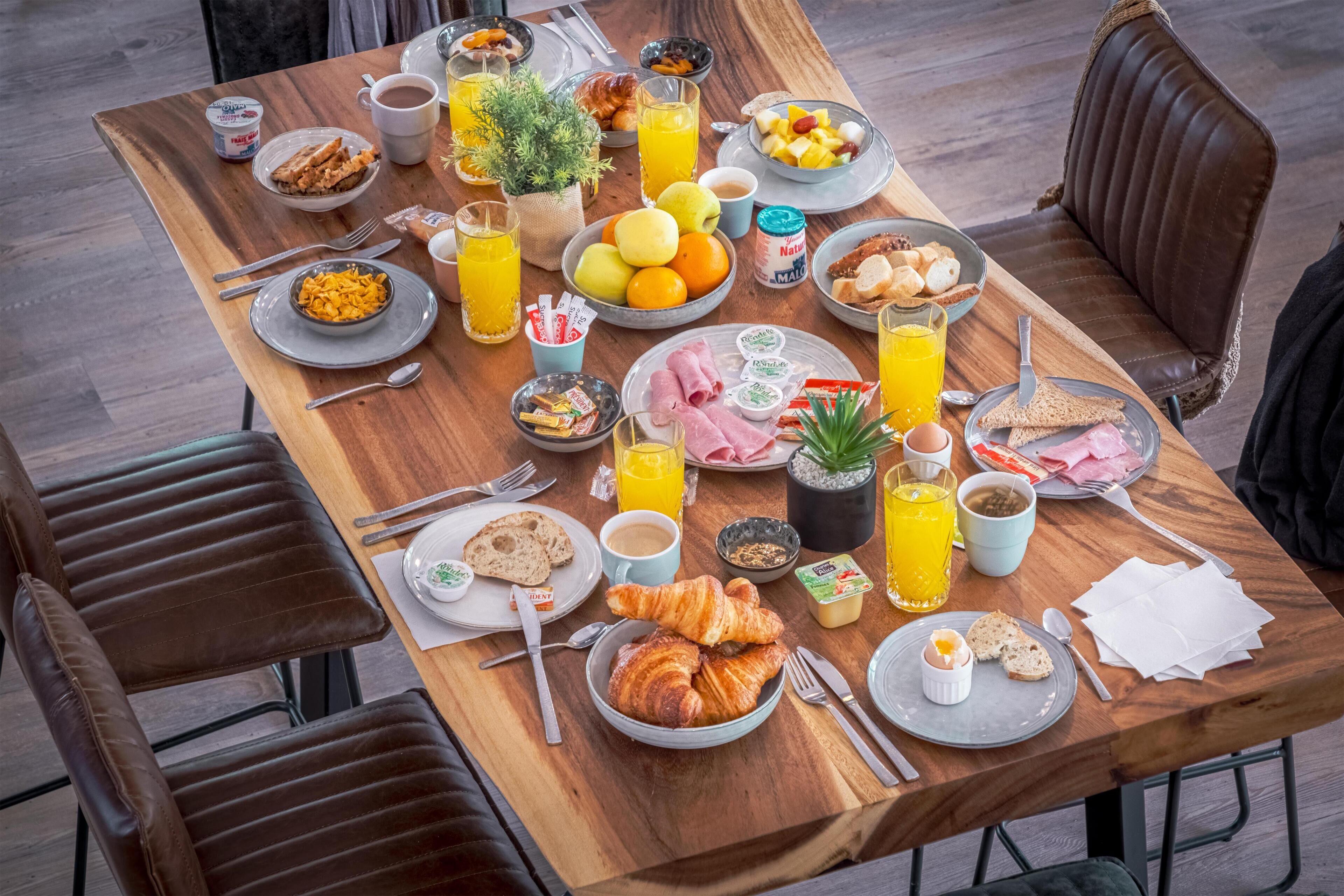 Una mesa de desayuno con diversos alimentos, bebidas y aderezos.