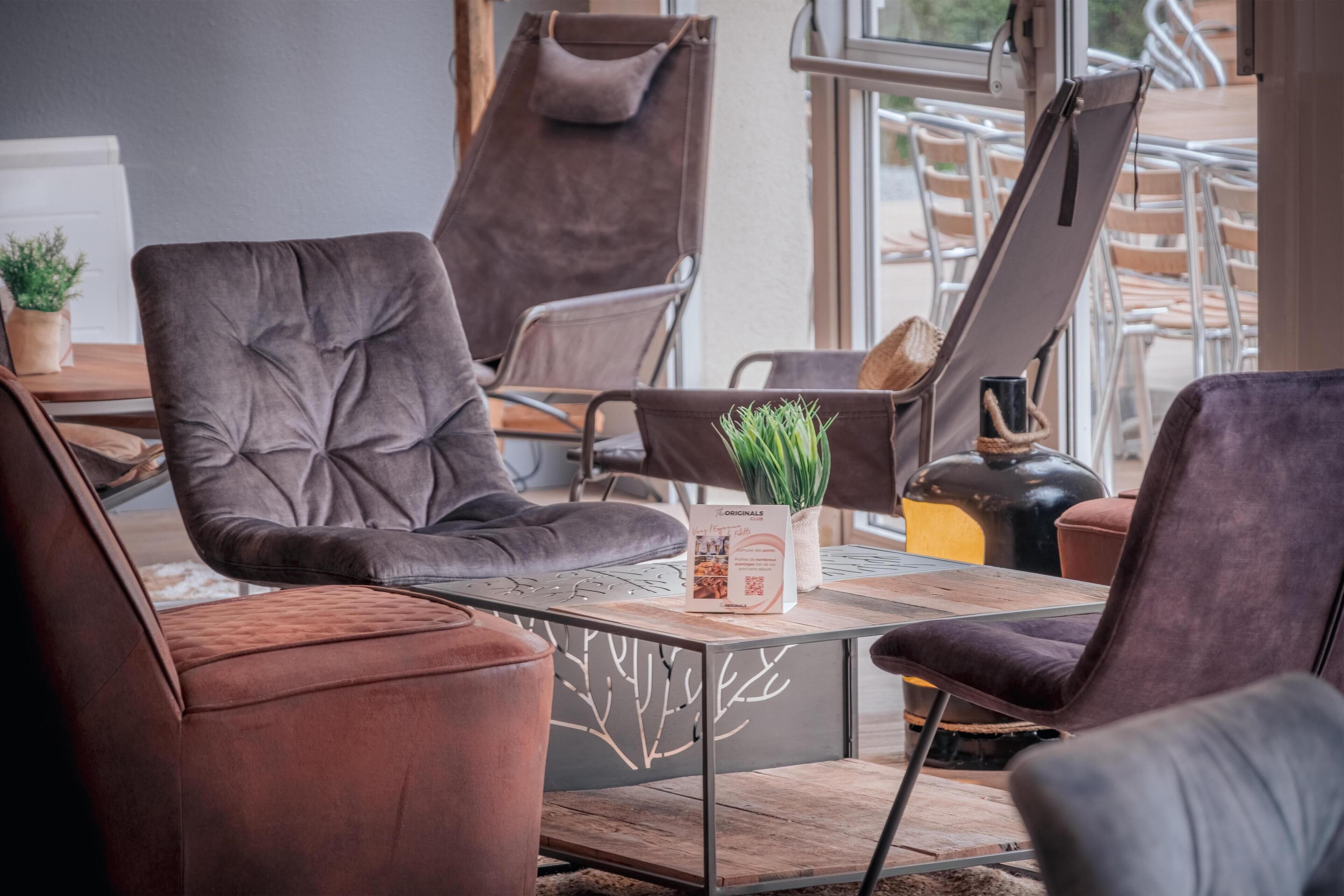 Un intérieur moderne avec un coin salon comprenant des fauteuils confortables et une table agrémentée d’un set de table.