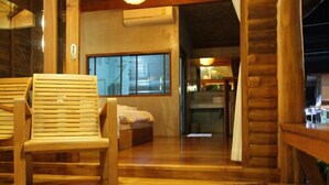 A wooden cabin interior with a large window, a wooden chair, a small rug, and a bed. - Tique Series Boutique Resort (Rayong)