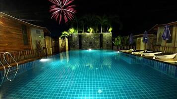 Relax by the pool surrounded by comfortable lounge chairs and umbrellas.