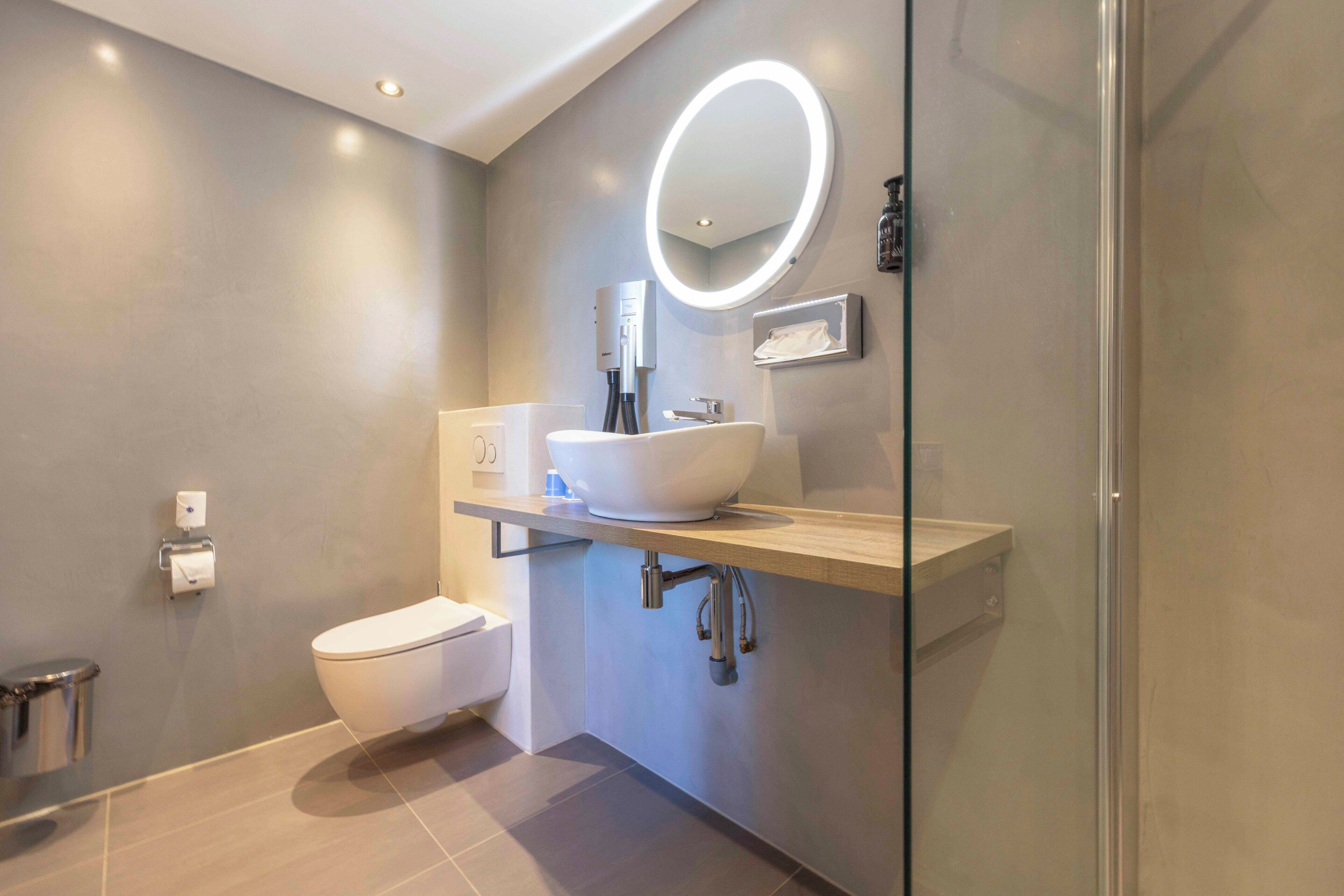 Ein modernes Badezimmer mit Toilette, Waschbecken und Dusche.