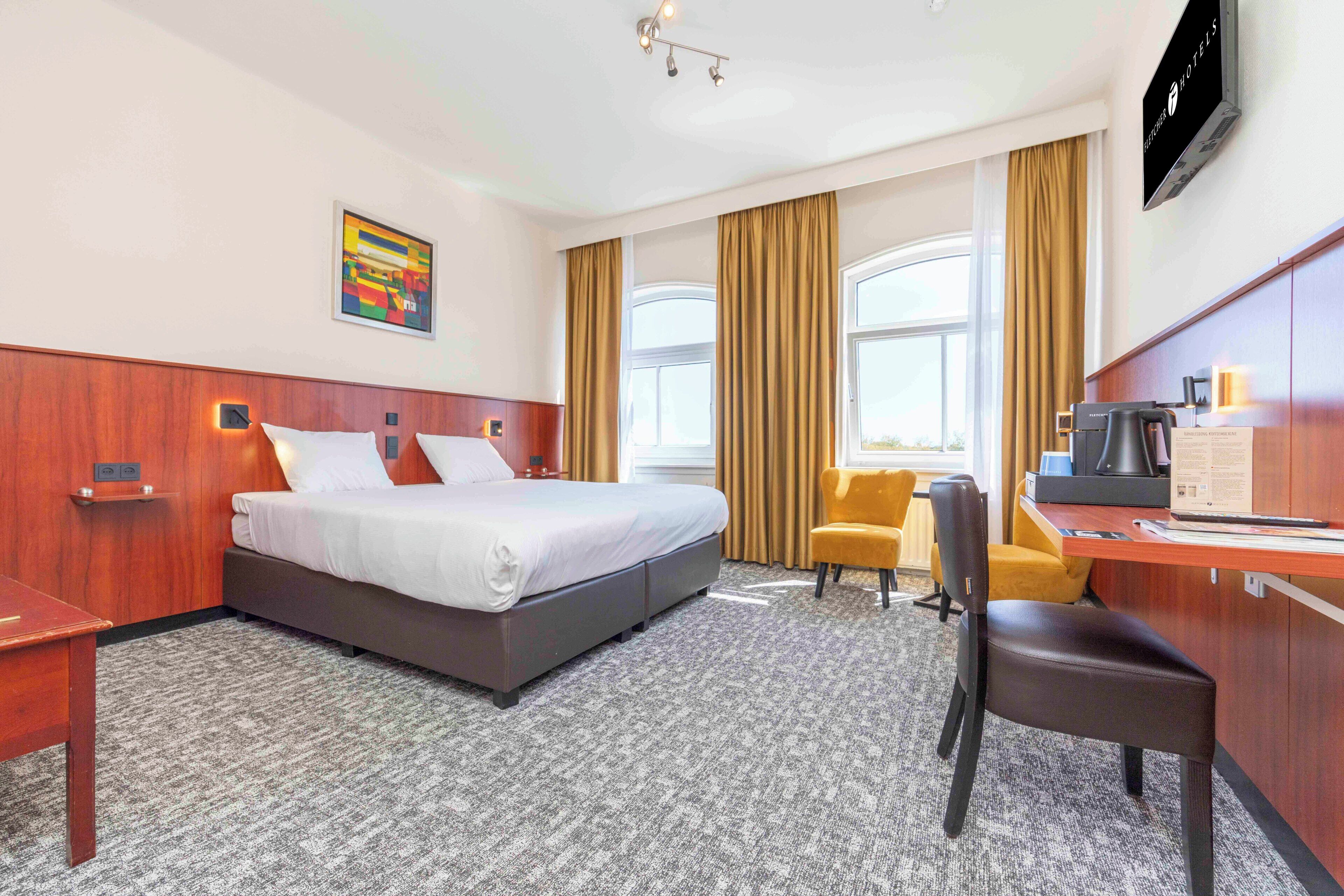 Une chambre d’hôtel équipée d’un lit, d’un bureau, d’une chaise et d’un téléviseur.