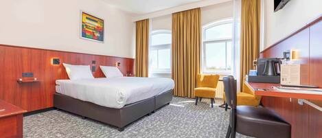Une chambre d’hôtel équipée d’un lit, d’un bureau, d’une chaise et d’un téléviseur.