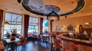 Un restaurante con un gran reloj circular en el techo, mesas y sillas de madera.