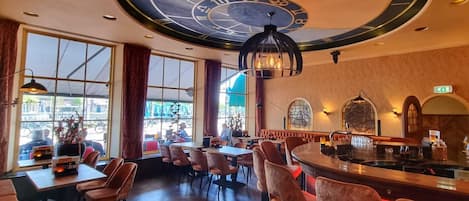 Ein Restaurant mit einer großen, runden Deckenuhr, Holztischen und -stühlen.
