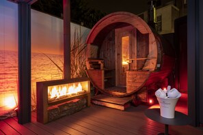 Een kamer in de vorm van een houten vat, met een open haard en een tafel met glazen.