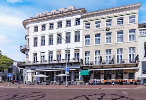 A multi-story hotel with a classic European architectural style, featuring balconies with flower boxes, outdoor seating, and a prominent hotel sign. - Fletcher Hotel De Nieuwe Doelen - Middelburg (Middelburg)
