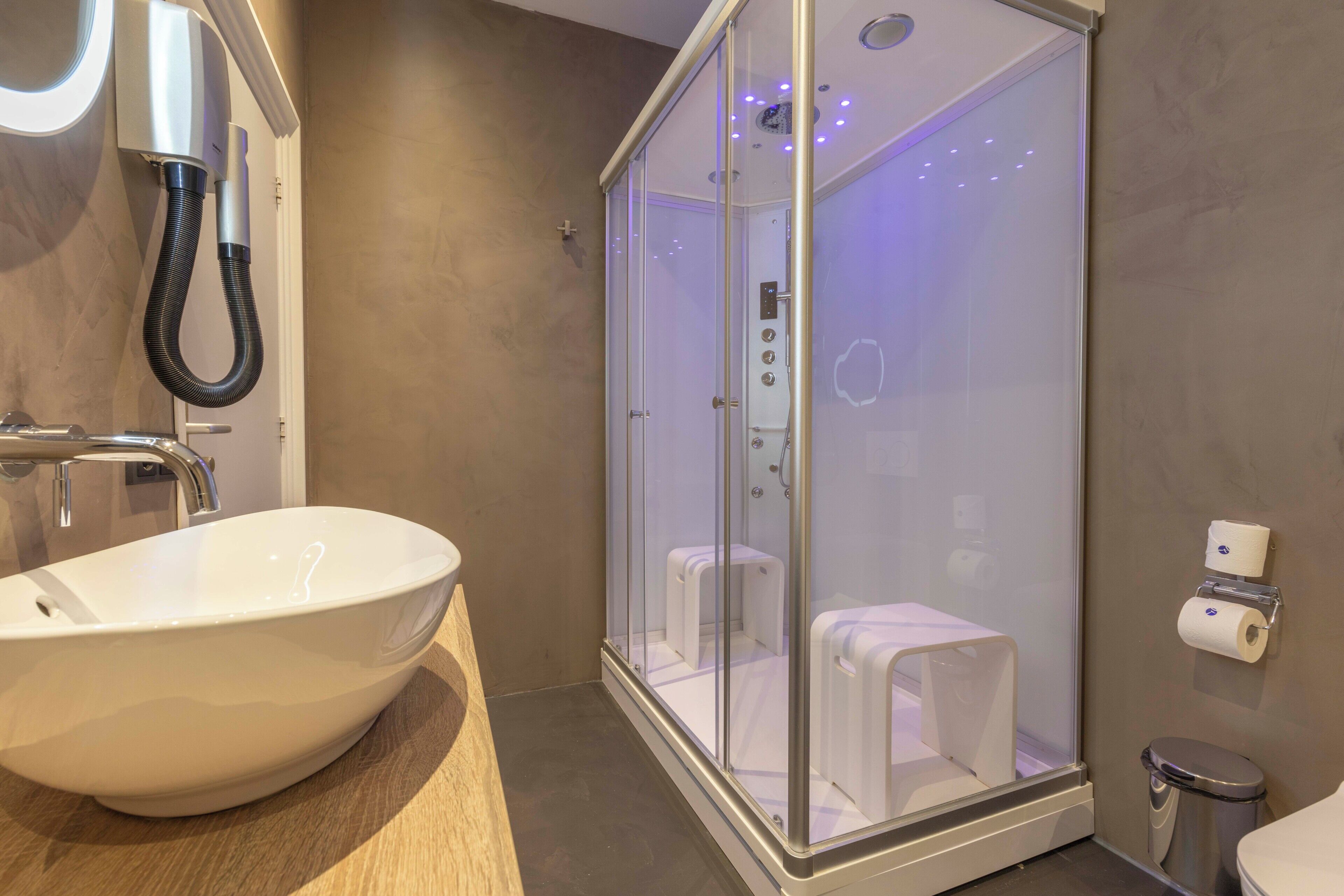 Ein modernes Badezimmer mit einem großen weißen Waschbecken, einer Duschkabine und einer Toilette.