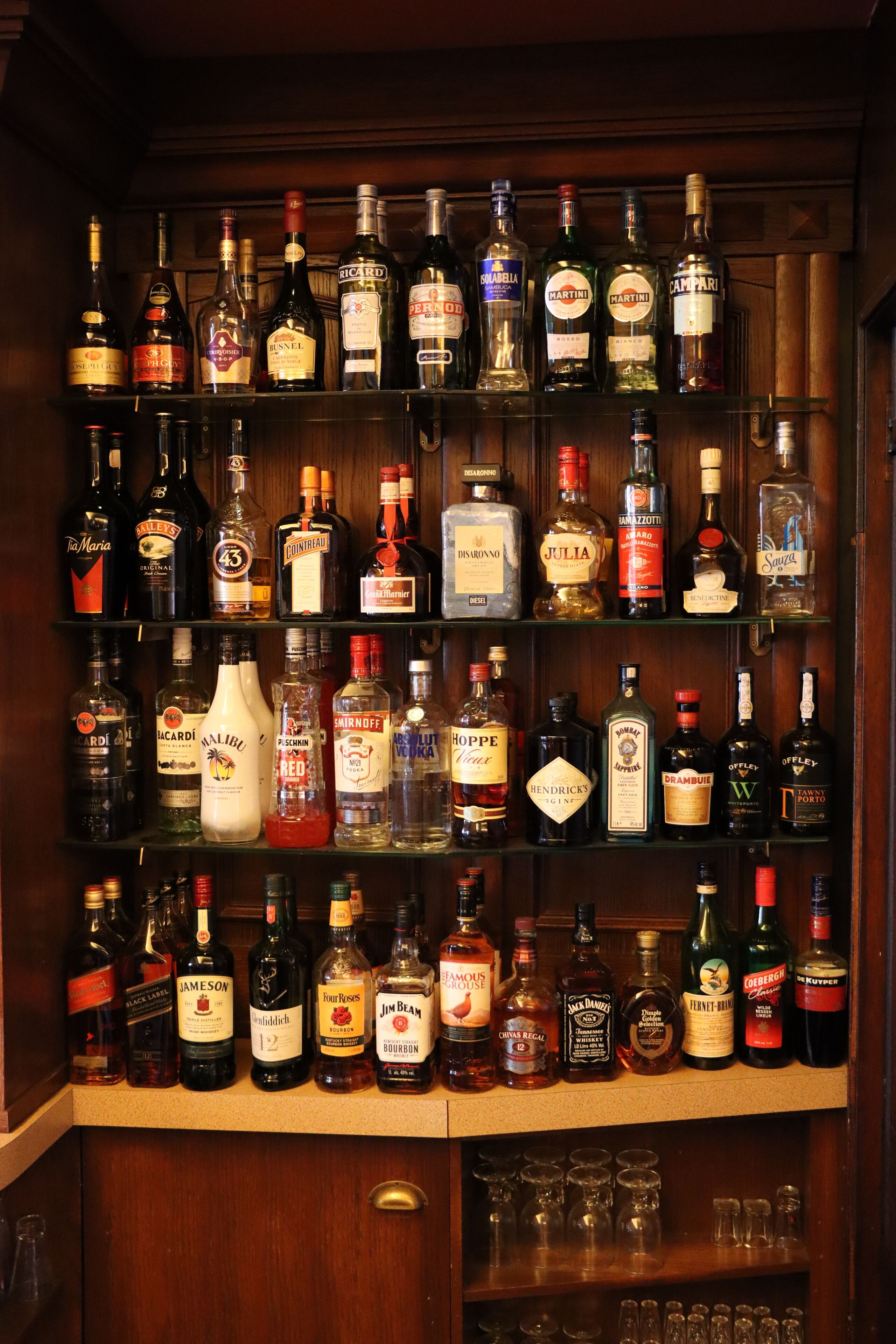 A bar with multiple shelves stocked with various liquor bottles.