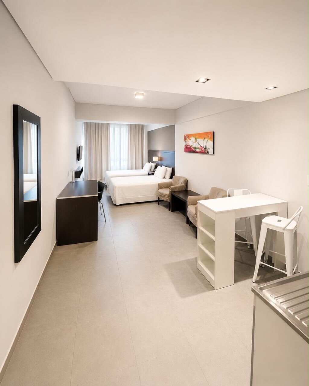 Ein modernes Hotelzimmer mit einem Bett, einem Schreibtisch, einem Sessel, einem kleinen Tisch und einem Bild an der Wand.