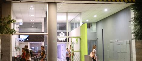La entrada del HOTEL NEU, con un diseño moderno que incluye una pared verde de acento y un área de recepción visible.