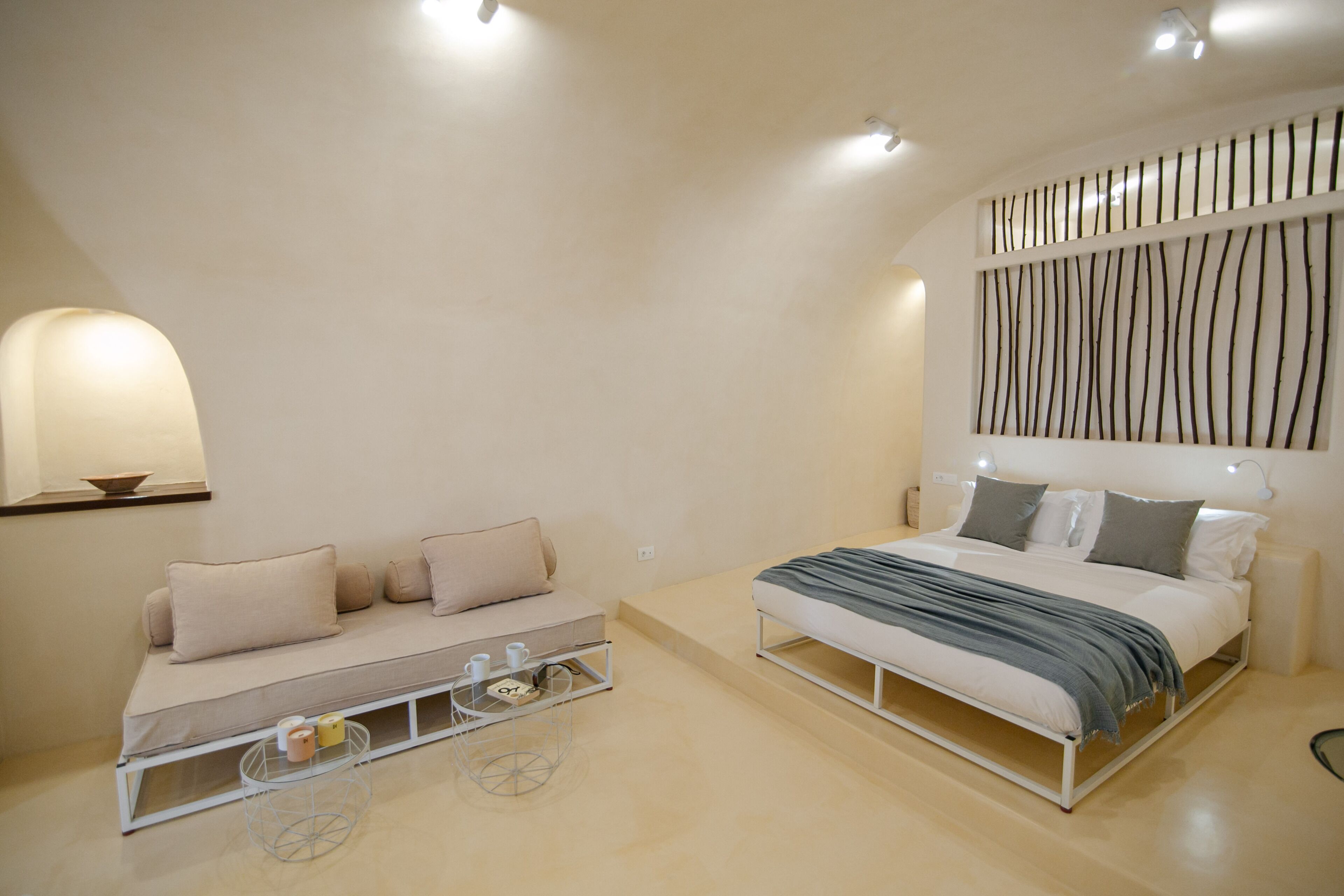 Un dormitorio moderno con una cama, un sofá y una mesita con una bandeja.