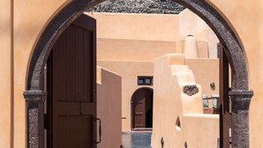 An arched entrance to a building with a tiled floor and a door. - Azalea Houses (Santorini)