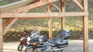 Een motorfiets geparkeerd onder een houten constructie.