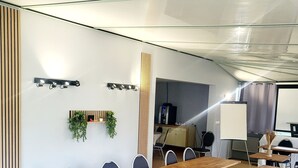 Een vergaderzaal met een lange houten tafel, zwarte stoelen, een whiteboard en een projectiescherm.