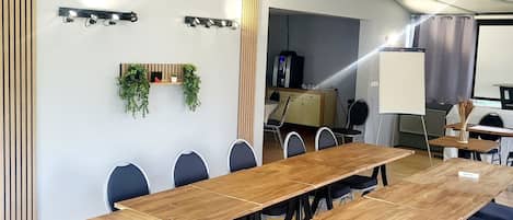 Un salón de conferencias con una larga mesa de madera, sillas negras, una pizarra y una pantalla para proyector.