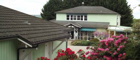 A two-story house with a green exterior and a grey roof.