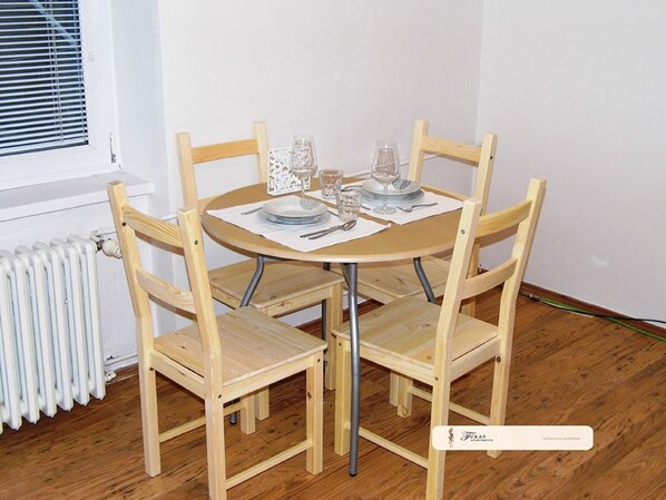 A small dining area with a round table and four wooden chairs. - FUKAS Apartments Nitra (Nitra)