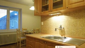 Una cuina amb armaris de fusta, una banyera doble i una zona de menjador amb taula i cadira.