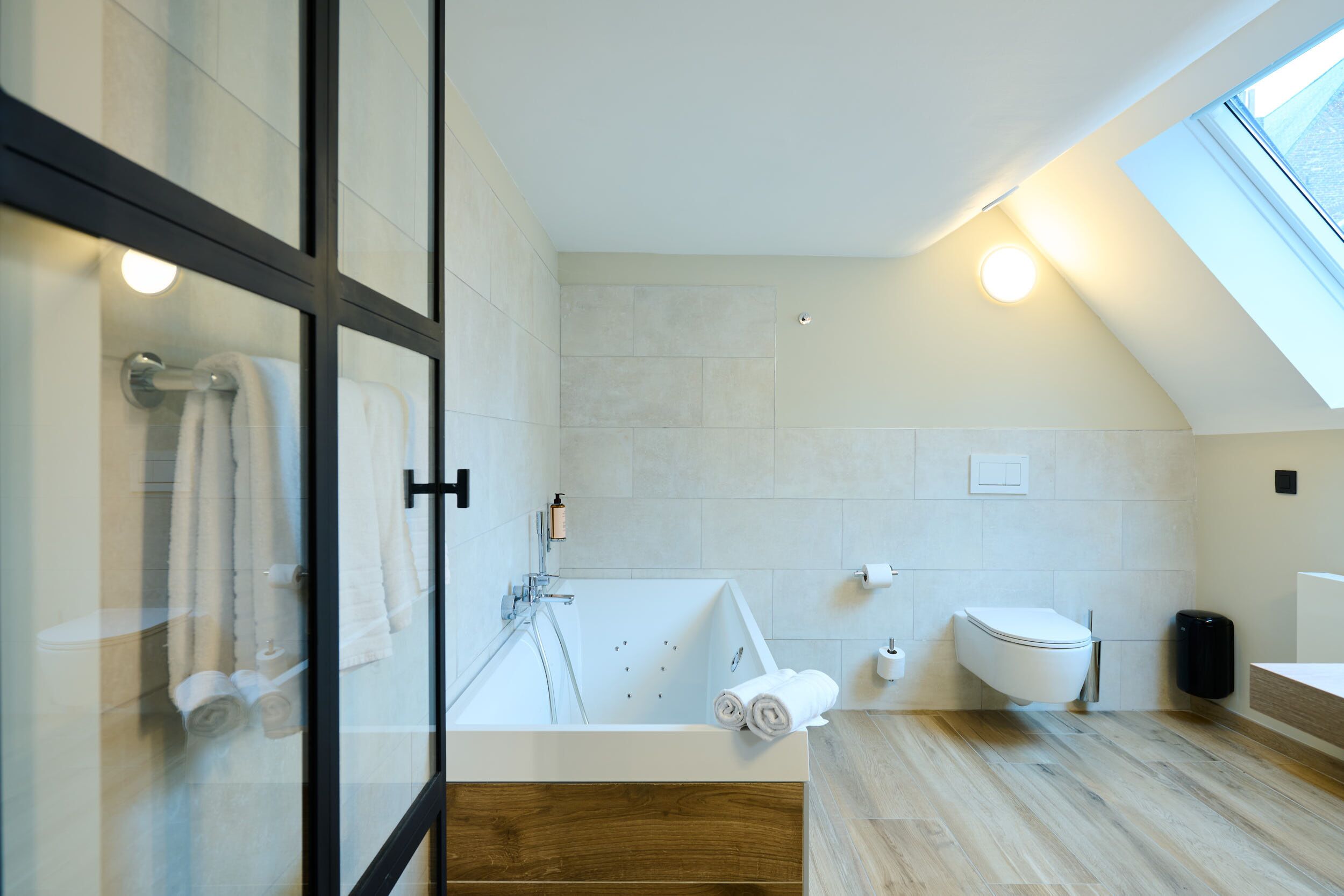 A modern bathroom with a glass shower enclosure, a freestanding bathtub, and a toilet.