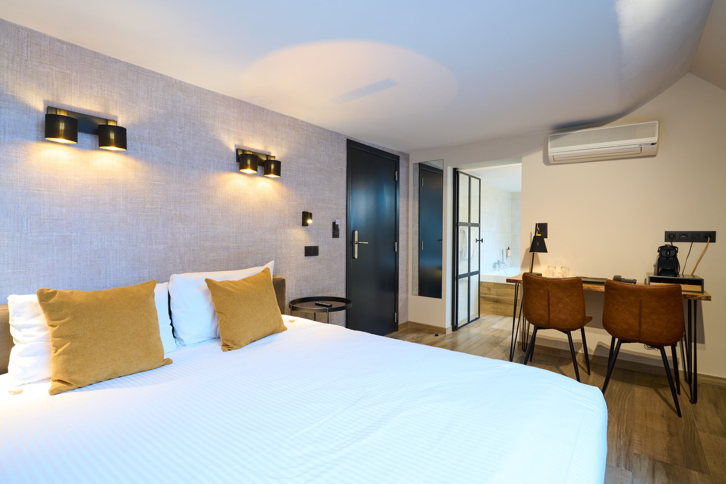 Camera d'albergo moderna con un ampio letto, una scrivania con sedie e vista all'esterno.