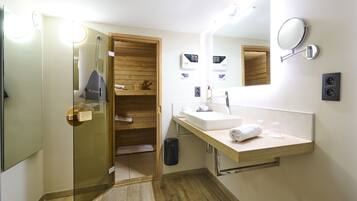 A modern bathroom with a glass shower enclosure, wooden shelving, a sink with a mirror, and a towel rack.