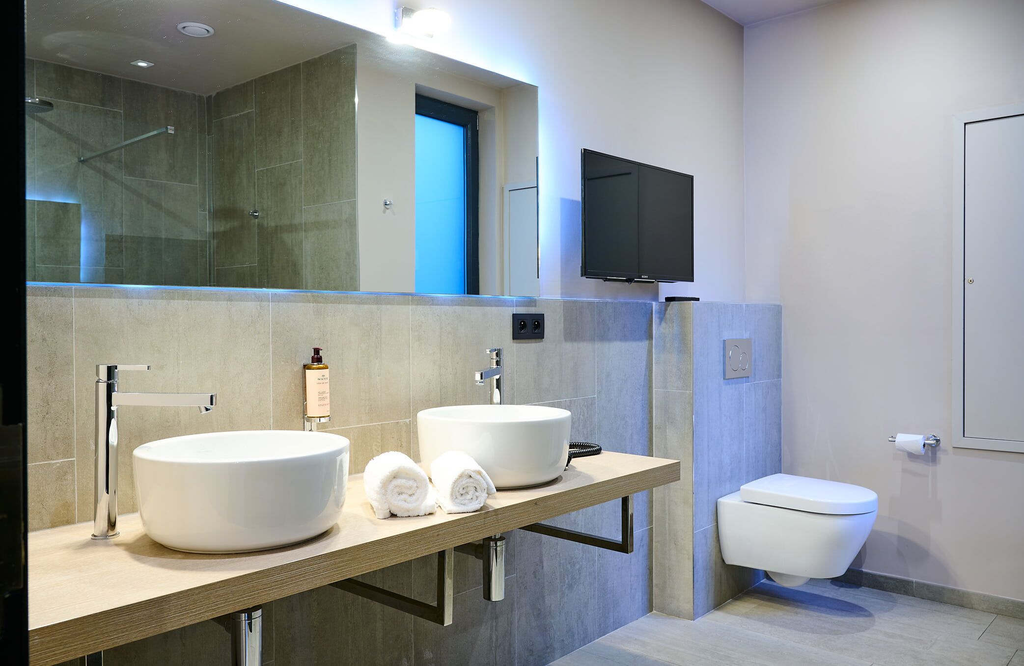 A modern bathroom with two sinks, a toilet, and a shower.