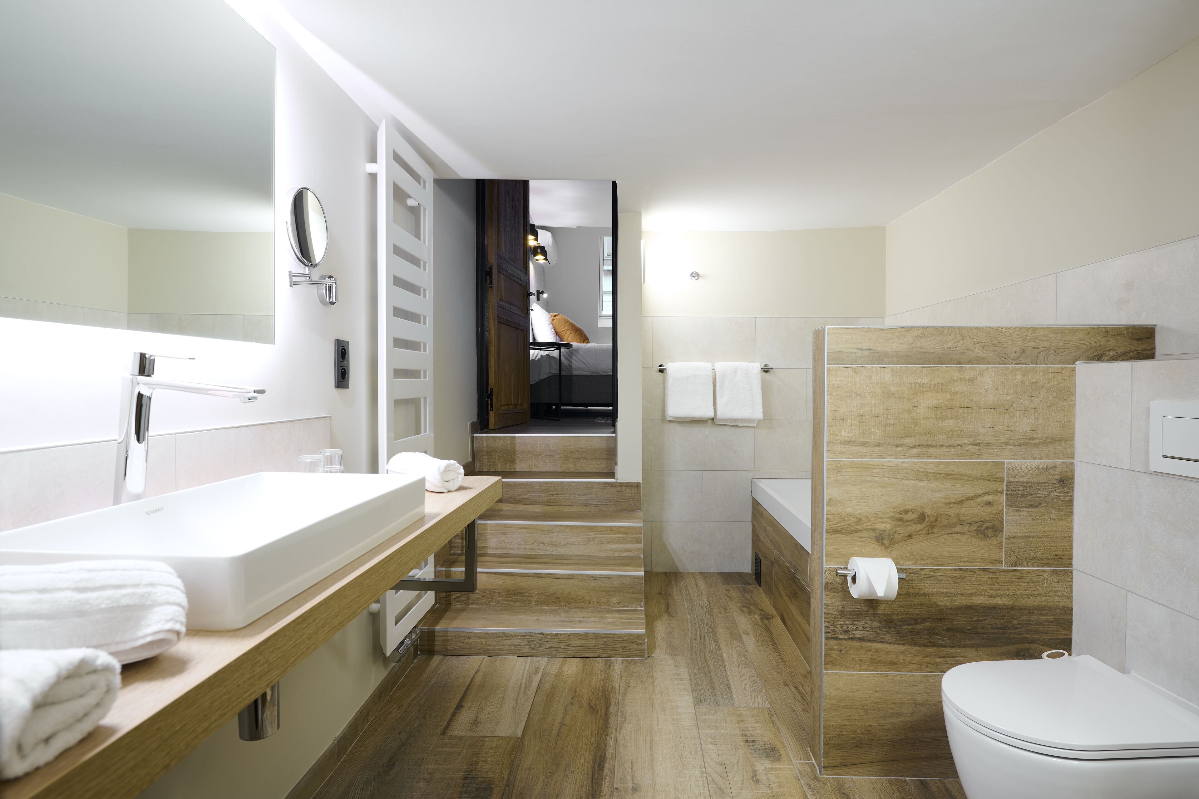 Un baño moderno con tocador de madera, un espejo grande y una zona de ducha separada.