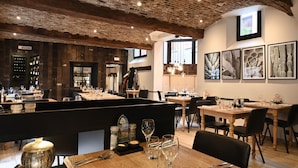 A restaurant with exposed brick ceilings, wooden tables, and black cushioned booths. - Les Tanneurs de Namur (Namur)