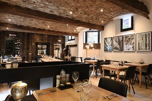Un restaurante con techos de ladrillo visto, mesas de madera y asientos tapizados en negro.