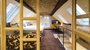 A bedroom with a bed, a desk, and a chair, a window, and a ceiling with exposed beams. - Les Tanneurs de Namur (Namur)