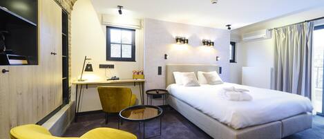 Una habitación de hotel moderna con cama, escritorio, silla y una mesita.