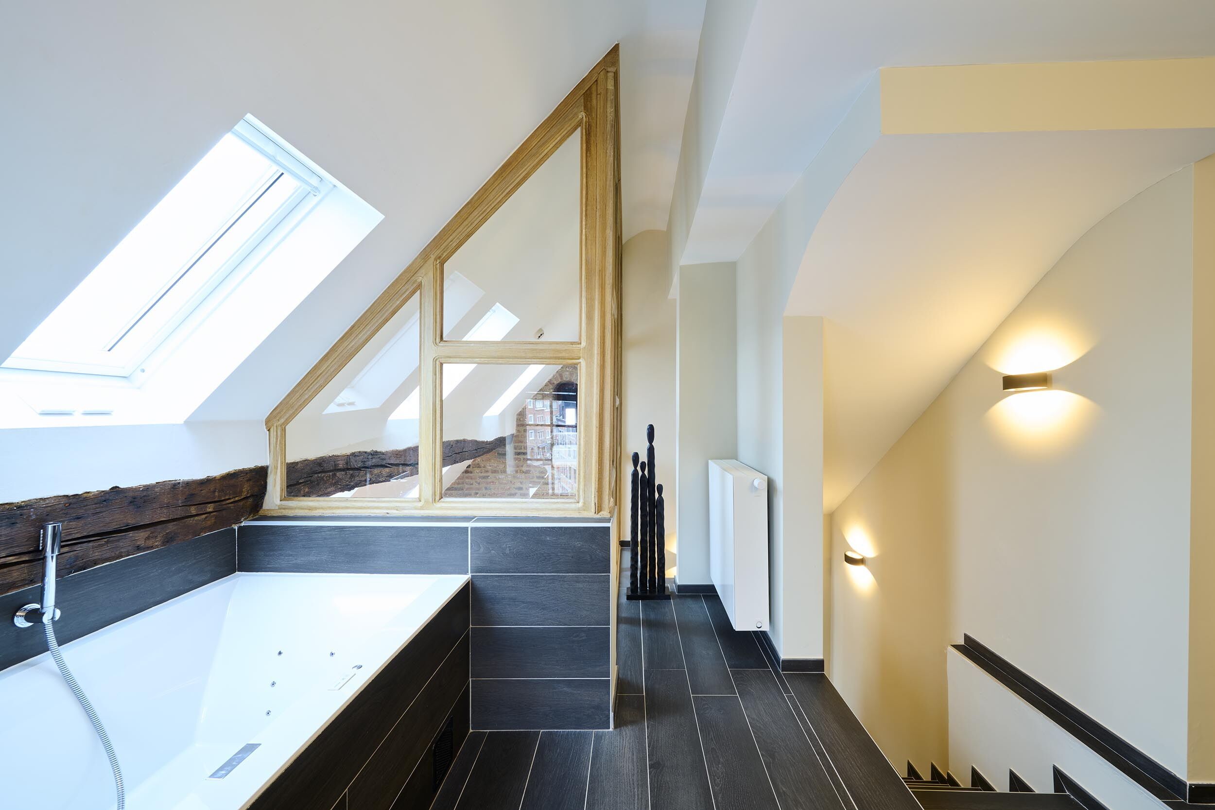 Een moderne badkamer met dakraam, een bad en een trap.