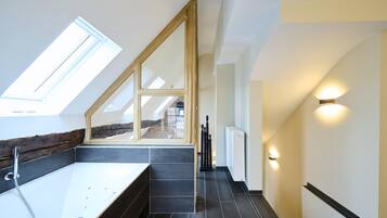 Een moderne badkamer met dakraam, een bad en een trap.