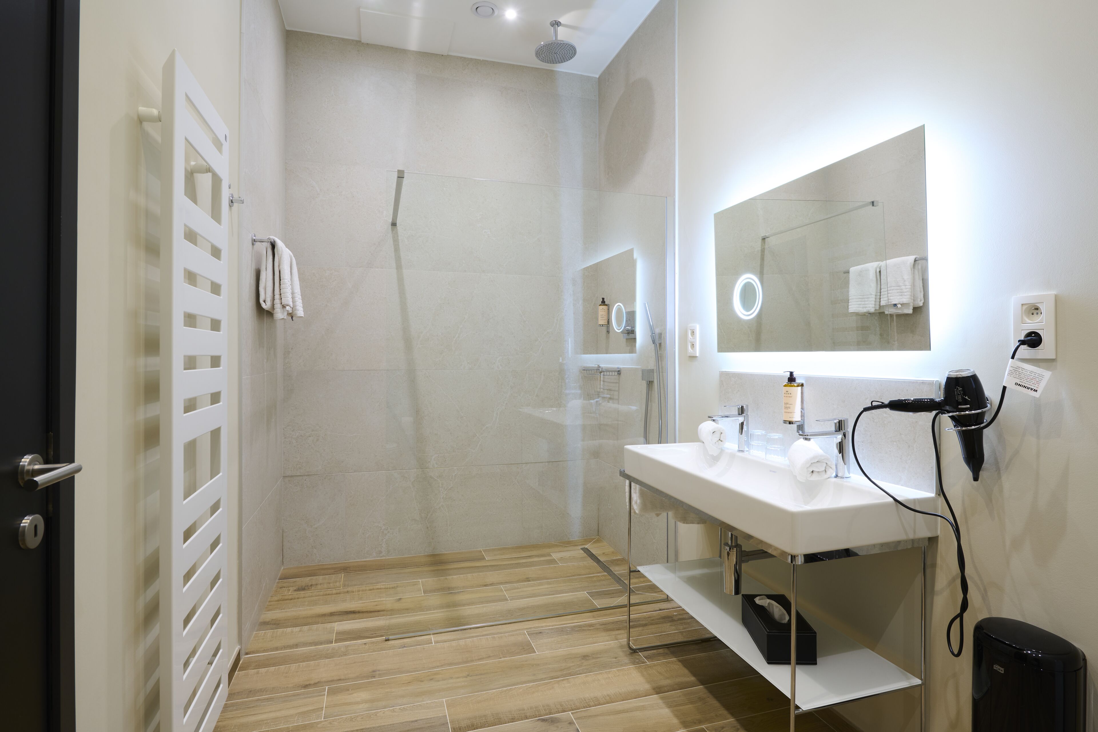 Une salle de bain moderne avec une douche, un lavabo et un miroir.