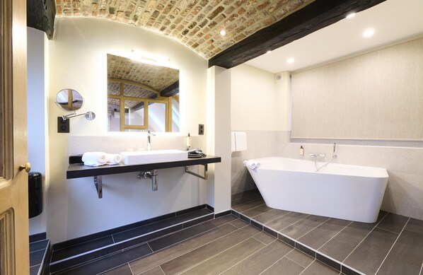 A modern bathroom with a freestanding bathtub, a vanity with a mirror, and a towel rack.