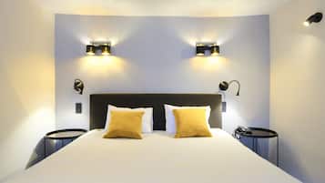 Una habitación de hotel moderna con una cama grande, dos lámparas de noche y una mesita con un teléfono.