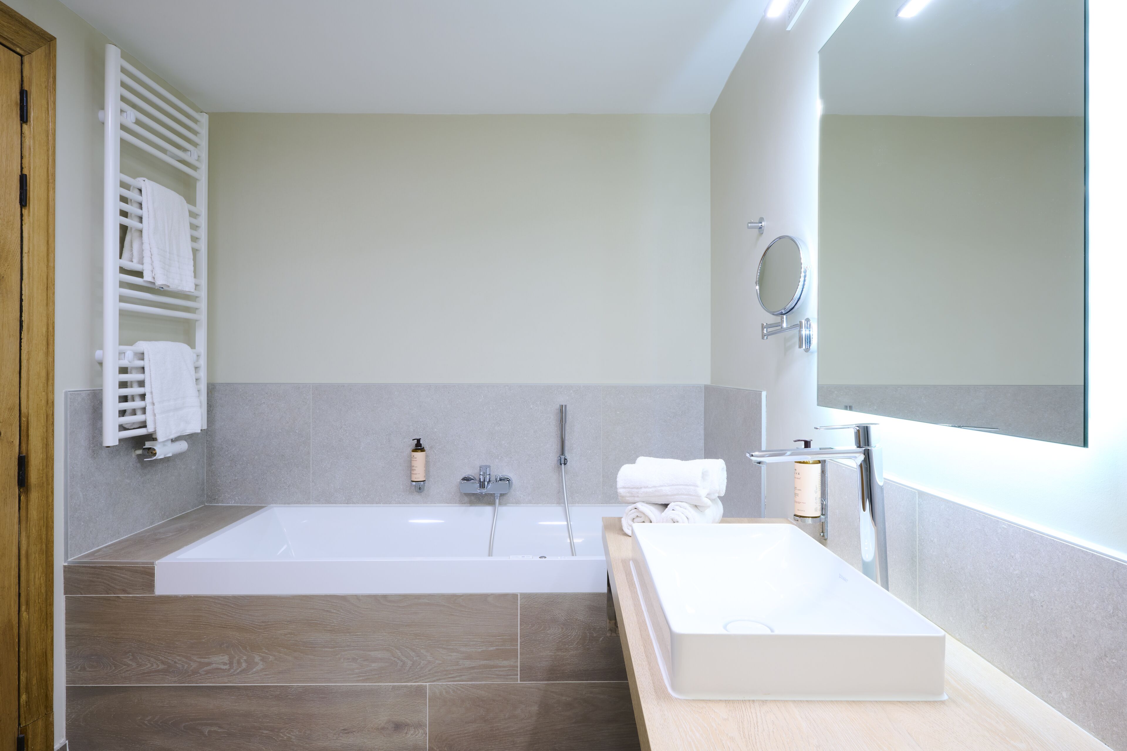 A modern bathroom with a large bathtub, a sink, and a mirror.