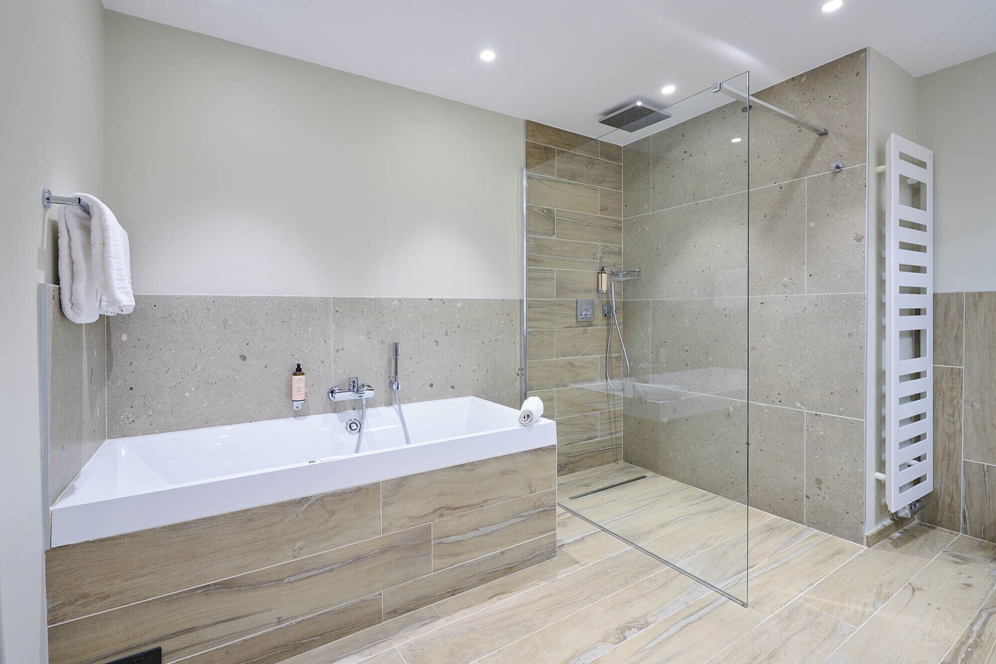 A modern bathroom with a glass-enclosed shower, a freestanding bathtub, and a towel rack.