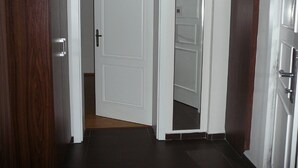 A hallway with a white door, a wooden door, and a mirror on the wall. - FUKAS Apartments MEDENA (Bratislava)