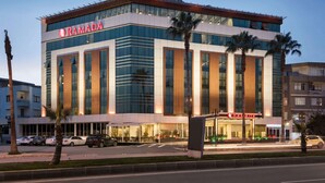 A modern building with the 'RAMADA' sign, featuring large windows, a flat roof, and a well-lit entrance. - Ramada by Wyndham Mersin (Mersin)