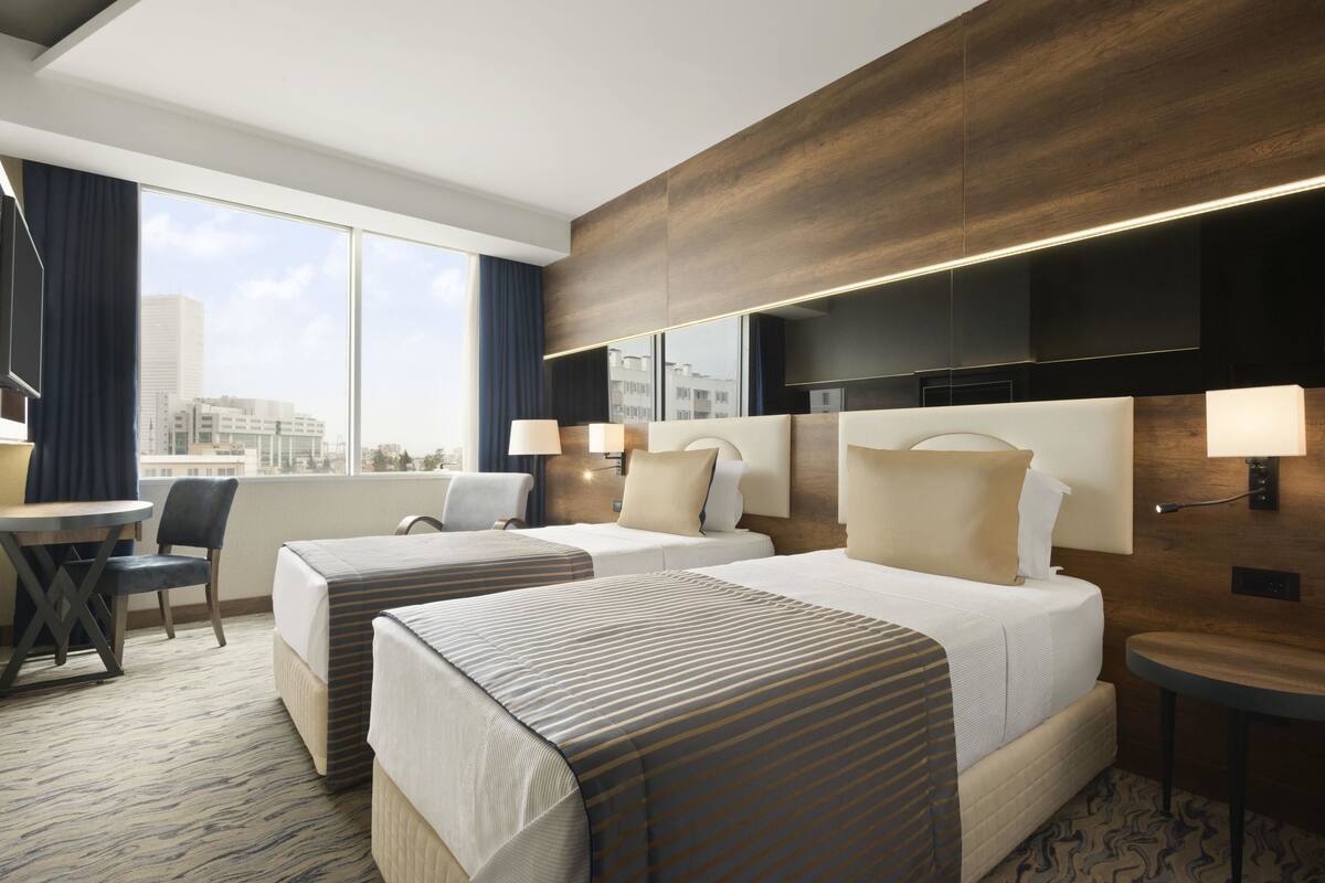 Een hotelkamer met twee bedden, een bureau en een stoel.