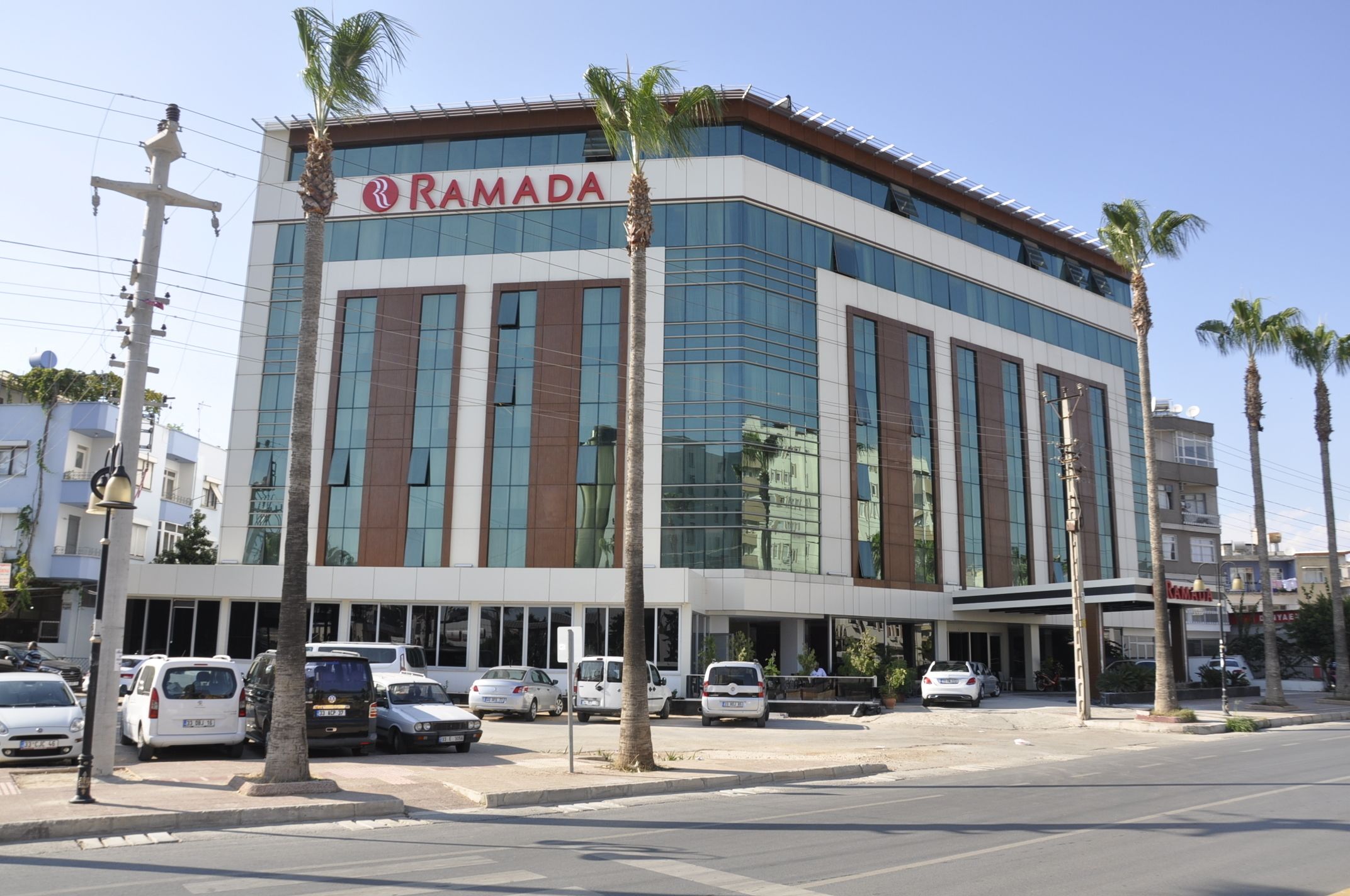 A modern building with the sign "RAMADA" on the facade, featuring large windows and a flat roof.