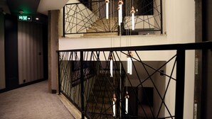 A modern hotel interior with a geometric railing design, a visible exit sign, and a patterned carpet. - Ramada by Wyndham Mersin (Mersin)