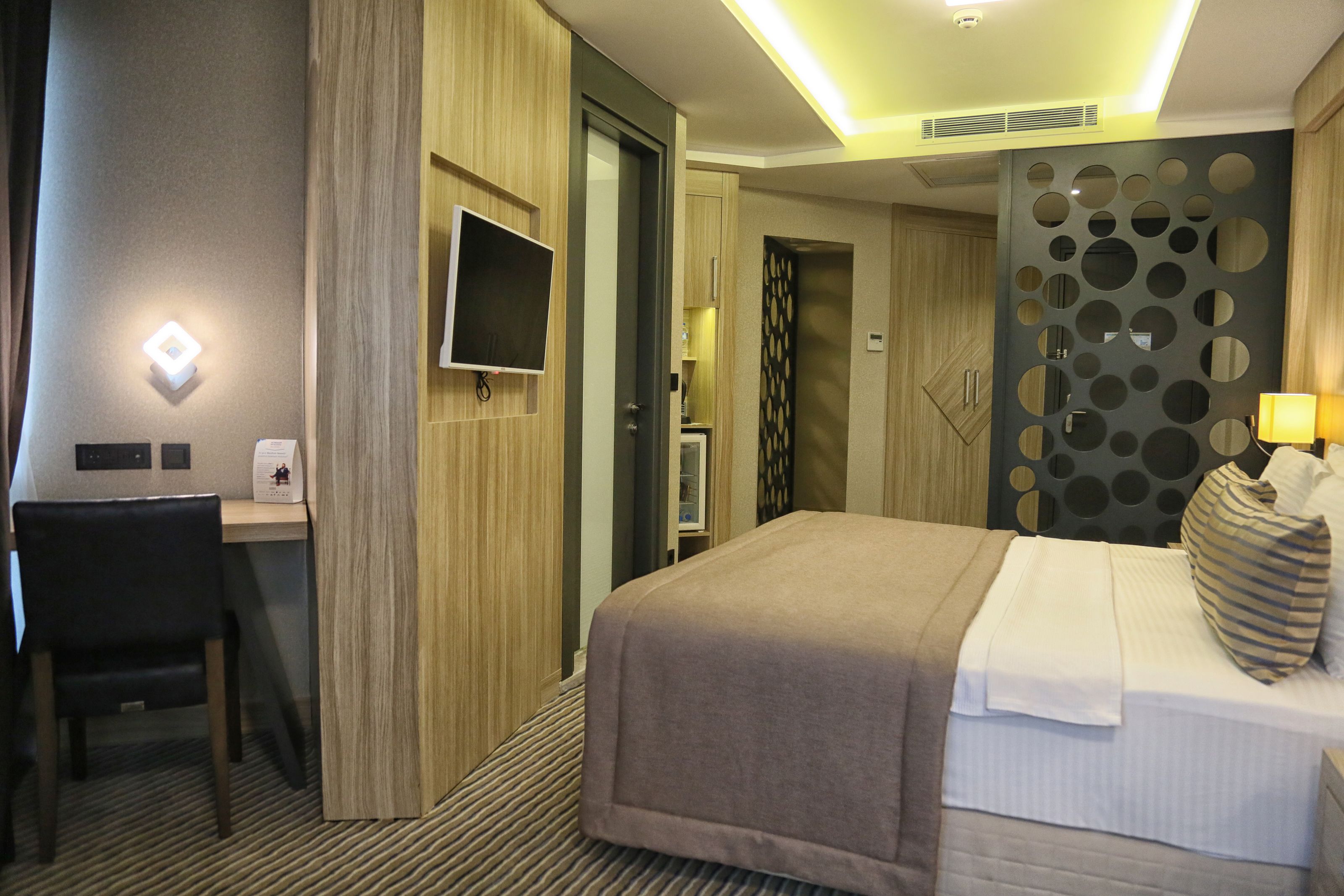 Ein Hotelzimmer mit Bett, Schreibtisch, Stuhl, Fernseher und einer Wandverzierung.