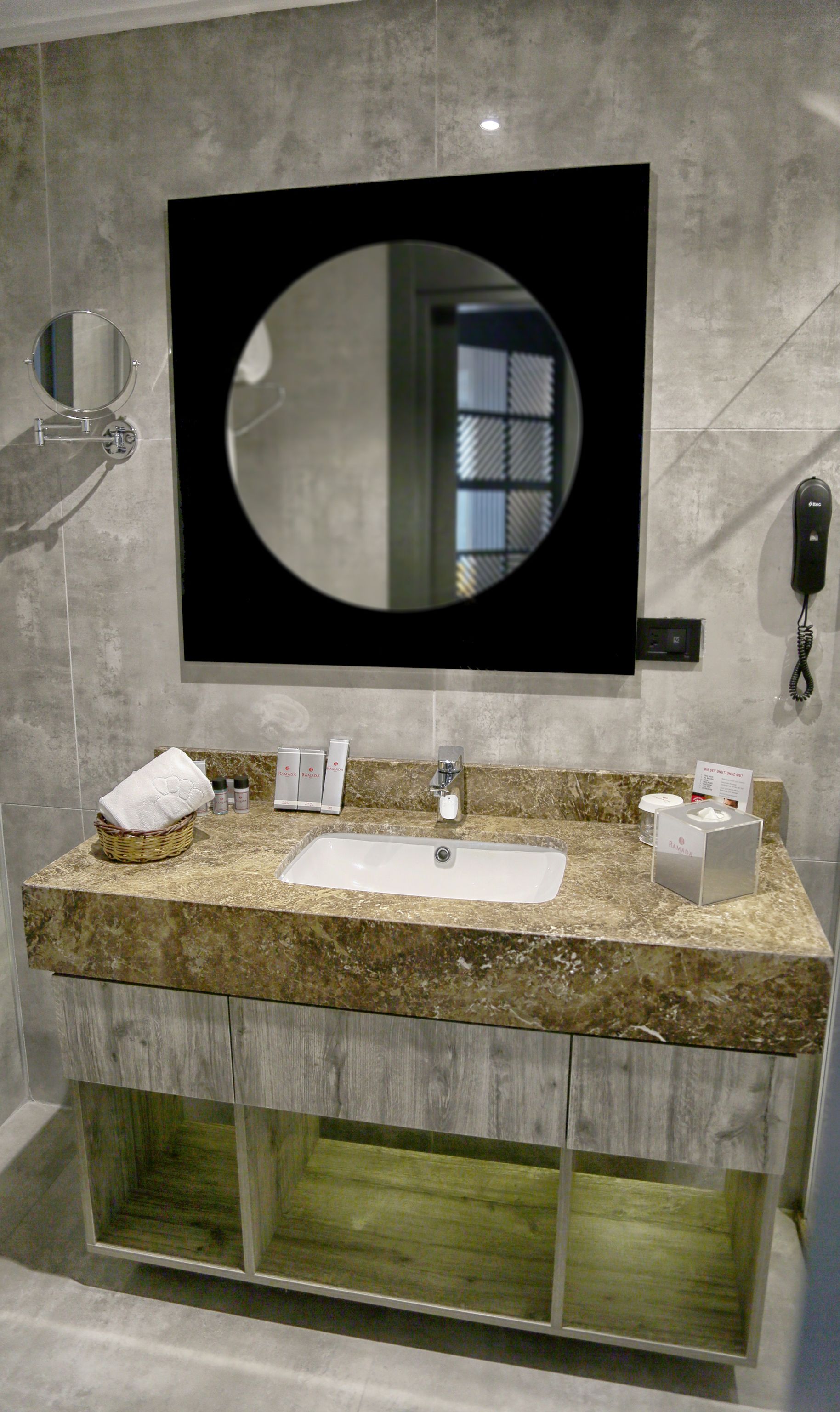 A bathroom with a large mirror, a sink, and a telephone.