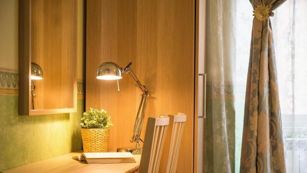 A wooden vanity with a lamp, a small plant, and a mirror. - Holiday Sunny Roma B&B (Rome)