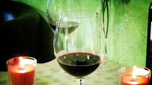 A glass of red wine on a table with two lit candles. - Holiday Sunny Roma B&B (Rome)